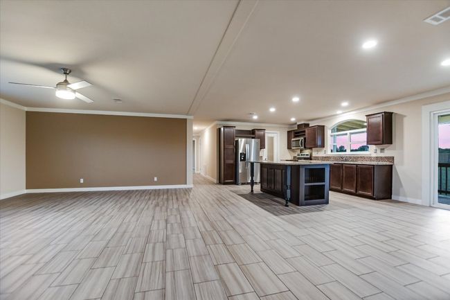 Kitchen featuring open floor plan, stainless steel appliances, crown molding, dark brown cabinets, and recessed​​‌​​​​‌​​‌‌​‌‌​​​‌‌​​‌‌​‌​​​​​‌ lighting | Image 7