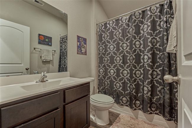 Full bath with solid surface countertop and tub/shower combo, centrally located between two of the secondary bedrooms. | Image 35