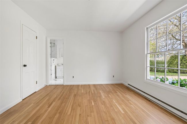 Unfurnished bedroom with a baseboard heating unit, baseboards, connected bathroom, and light wood-type flooring | Image 13