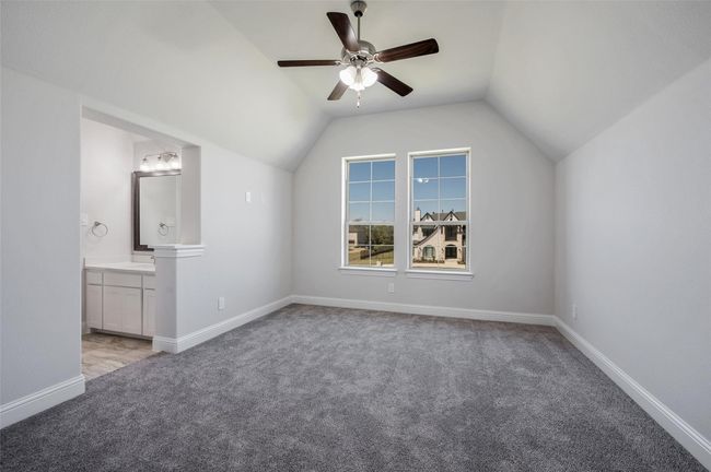 Unfurnished bedroom featuring light colored carpet, lofted ceiling, connected bathroom, baseboards, and ceiling fan | Image 27