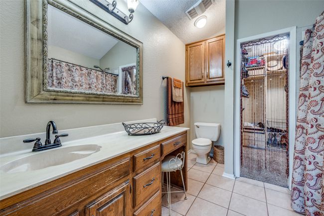 Full bathroom featuring tile patterned floors, toilet, a textured ceiling, and vanity | Image 11