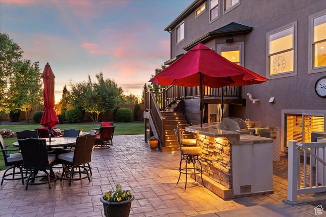 Patio terrace at dusk featuring stairway, an outdoor kitchen, a bar, outdoor dining area, and grilling area | Image 63