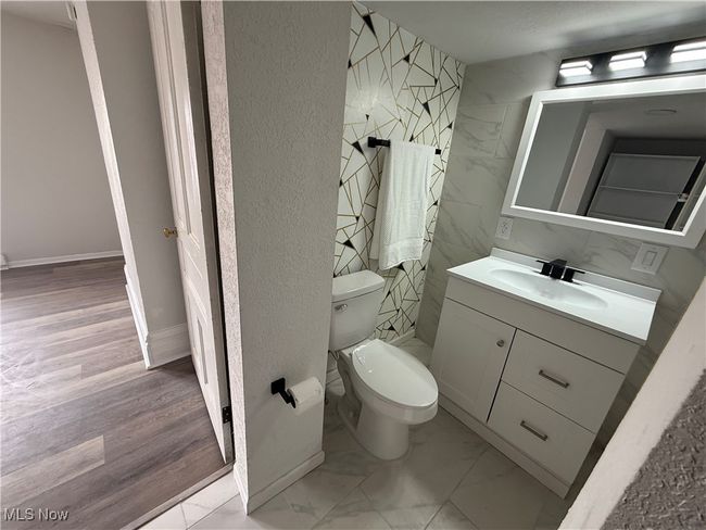 Bathroom featuring marble finish floor, toilet, a textured wall, and vanity | Image 4