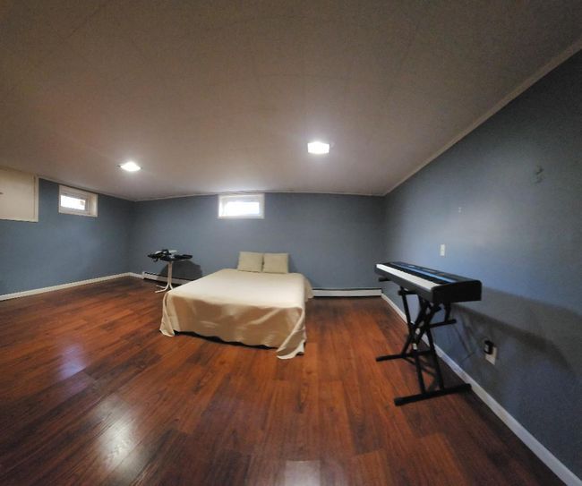 Bedroom with wood finished floors, baseboards, and baseboard heating | Image 10