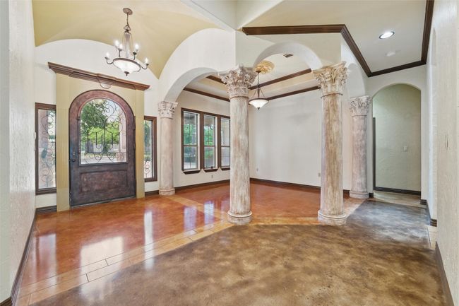 Entryway with ornate columns, arched walkways, ornamental molding, and finished concrete flooring | Image 6