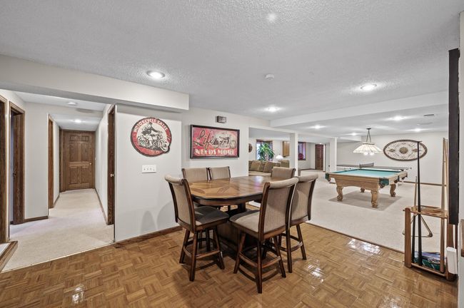Another view of the lower level from the wet bar/kitchen area. Recessed lighting keeps this space feeling clean and polished - space for days!! Down the hallway to the left is one of the staircases to the main floor, bathroom, 2 bedrooms & laundry | Image 39