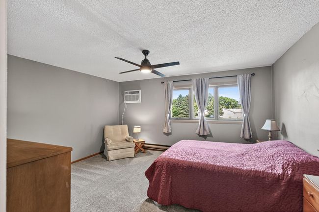 The primary bedroom is generously sized and includes a newer ceiling fan with a light, newer carpet, new Anderson windows, and a newer AC unit. | Image 12