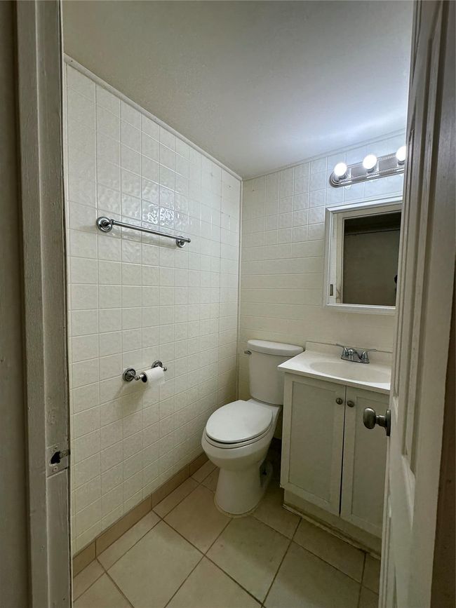 Half bathroom featuring toilet, vanity, tile walls, and tile patterned floors | Image 12