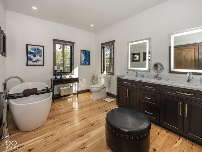 full bath featuring double vanity, a freestanding tub, hardwood / wood-style floors, toilet, and baseboards | Image 20