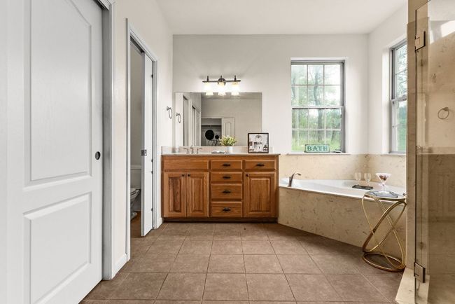 Bathroom with vanity, toilet, tile patterned flooring, and a garden tub | Image 26