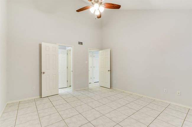 Unfurnished primary bedroom featuring a towering ceiling, a ceiling fan, light tile patterned floors | Image 18