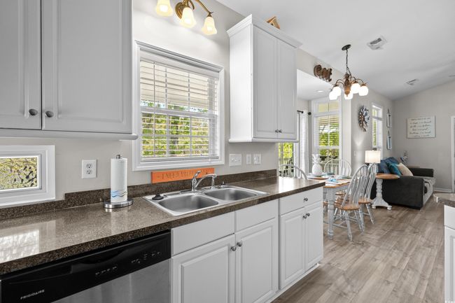 Kitchen featuring light wood-style floors, a sink, white cabinetry, and black appliances | Image 26