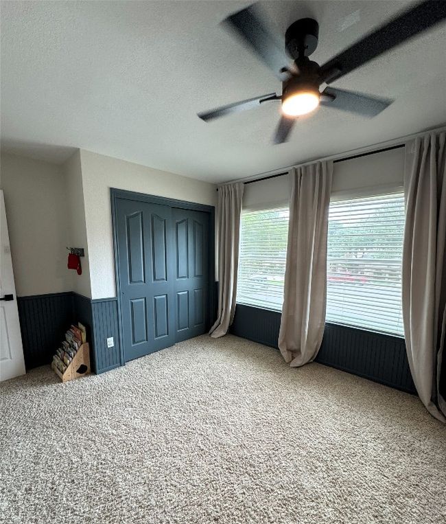 Upstairs Guest Bedroom #2 featuring a textured ceiling, carpet floors, ceiling fan, a closet, and wainscoting. | Image 20