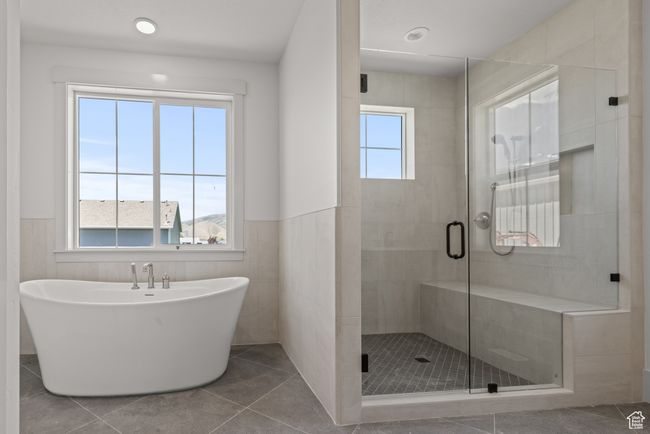 Full bathroom with a stall shower, a freestanding bath, a wainscoted wall, and tile patterned flooring | Image 22