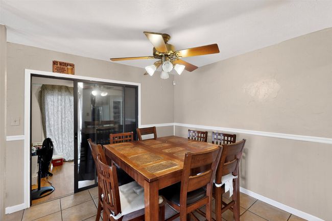 Dining room with light tile patterned floors and a ceiling fan | Image 7