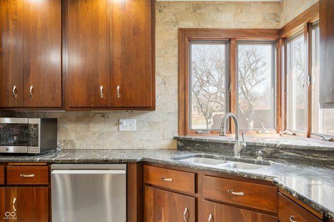 kitchen with a sink, dark stone countertops, tasteful backsplash, stainless steel appliances, and brown cabinetry | Image 17