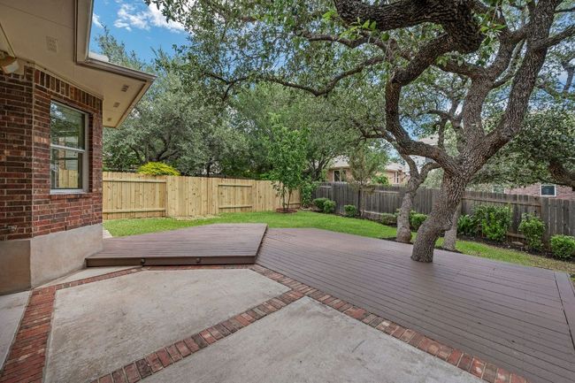 Step outside to your private backyard retreat with a covered patio, extended deck, mature trees, and lush landscaping. Unwind in the optional hot tub, perfect for Texas evenings. | Image 27