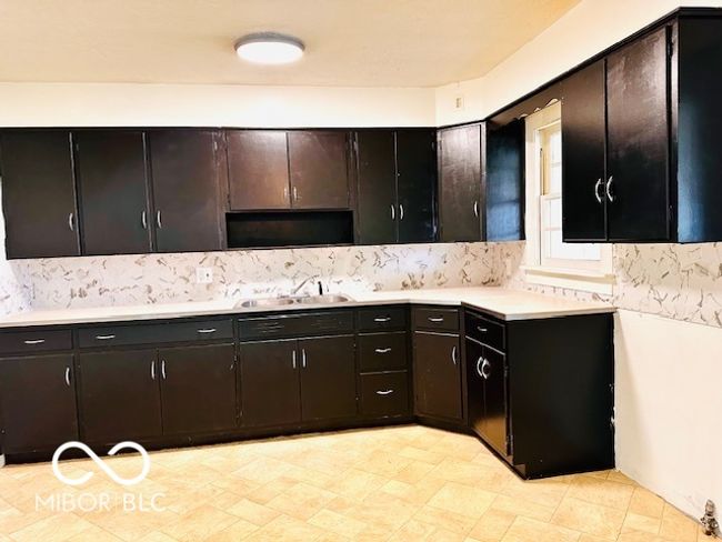kitchen with a sink, light countertops, decorative backsplash, and light flooring | Image 16