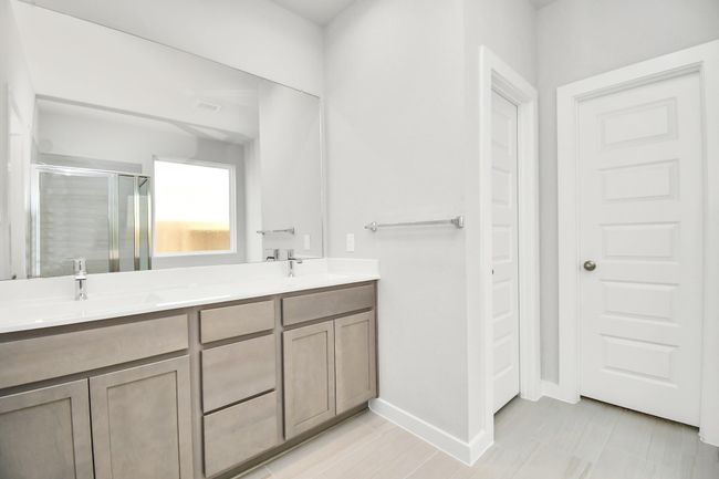 The sophisticated vanity, featuring double sinks, dark-colored countertops, contemporary hardware, and bright recessed lighting, adds both style and functionality to the space. | Image 24