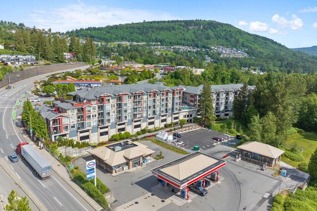 Drone / aerial view of a forest, a mountainous background, and apartment complex / building | Image 5