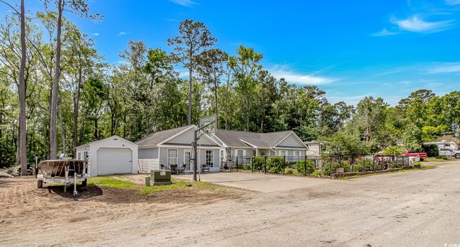 View of front of home featuring view of wooded area, an outdoor structure, a garage, and a shingled roof | Image 33
