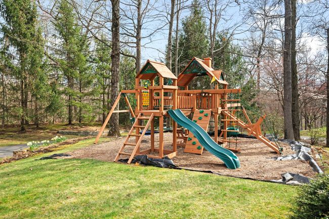 This beautifully landscaped front yard features a custom playset surrounded by mature trees—perfect for outdoor family fun. | Image 41