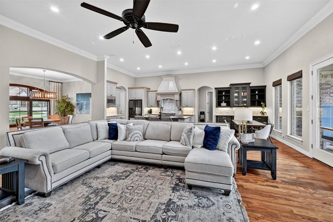Living room with arched walkways, light wood-style flooring, a chandelier, recessed lighting, and a ceiling fan | Image 8