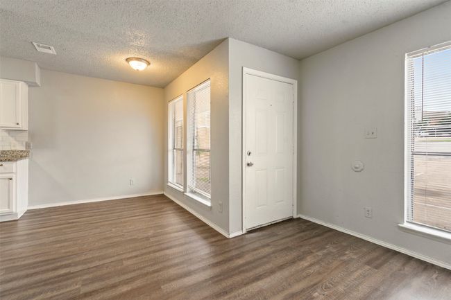 Unfurnished dining area featuring dark wood-style flooring, plenty of natural light, a textured ceiling, and baseboards | Image 8
