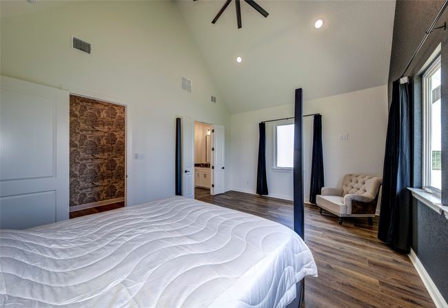 Bedroom featuring dark hardwood / wood-style floors, high vaulted ceiling, multiple windows, and connected bathroom | Image 13