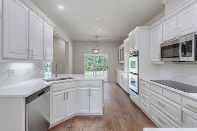 Kitchen with appliances with stainless steel finishes, a sink, dark wood-type flooring, white cabinets, and recessed lighting | Image 11