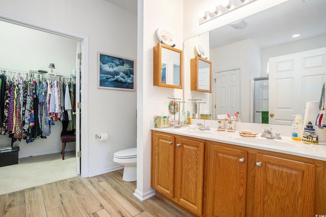 Bathroom featuring double vanity, wood finished floors, a walk in closet, and a shower with shower door | Image 21