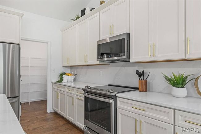 Kitchen with stainless steel appliances, dark wood-style floors, and white cabinets | Image 18