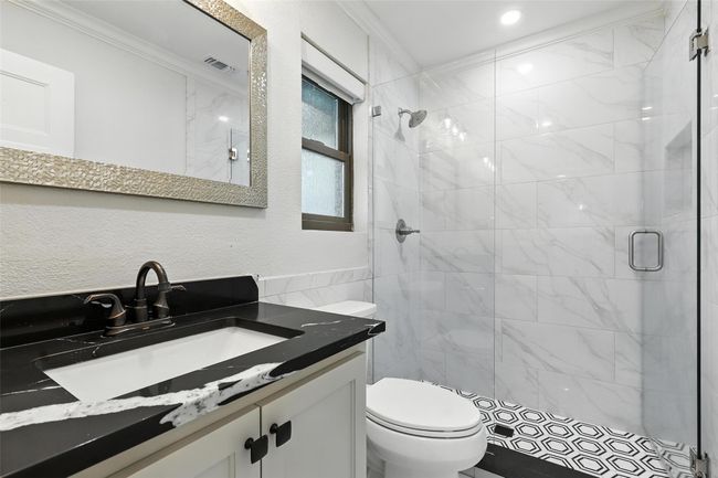 Bathroom featuring tile walls, a stall shower, vanity, crown molding, and a textured wall | Image 33