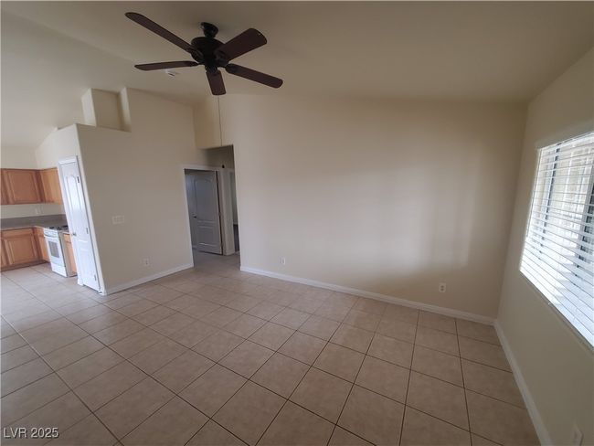 Spare room featuring baseboards, high vaulted ceiling, light tile patterned floors, and a ceiling fan | Image 6