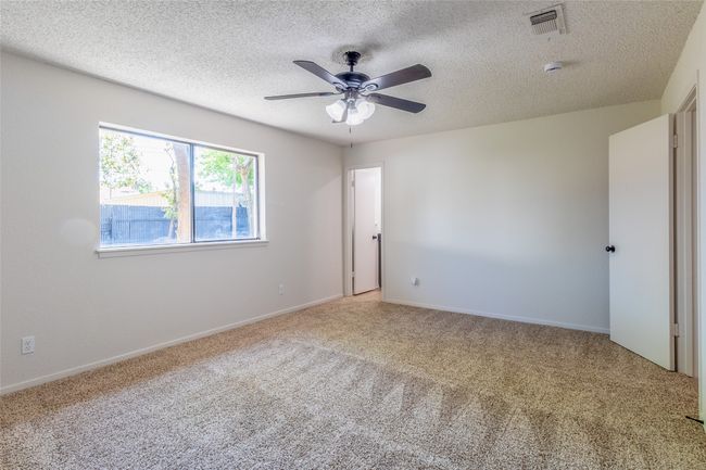Carpeted spare room featuring a textured ceiling, visible vents, a ceiling fan, and baseboards | Image 15
