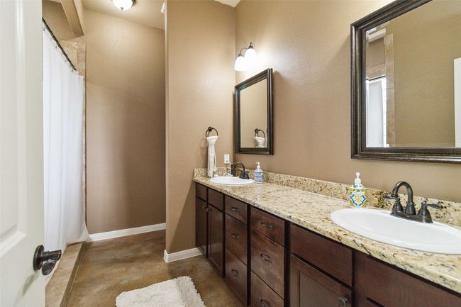 Bathroom with double vanity, baseboards, concrete flooring, and a shower with shower curtain | Image 24