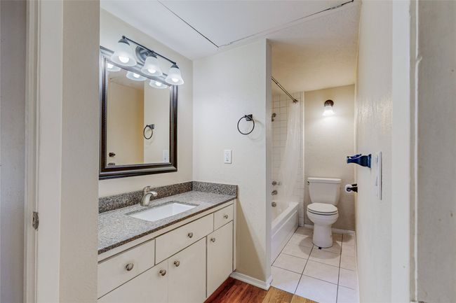 A minimalist wet room layout showcasing a vanity unit with stylish lighted mirror on the wall, towel racks, a bathtub and a toilet. | Image 20