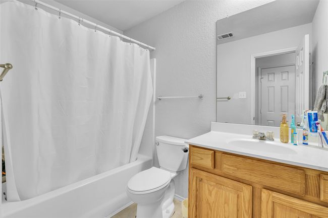 Bathroom with vanity, shower / bath combination with curtain, and a textured wall | Image 24