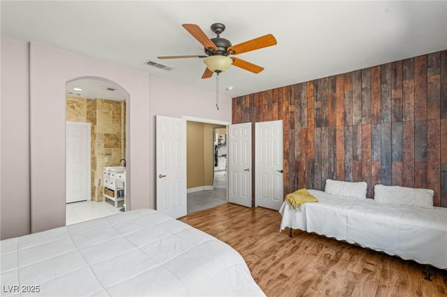Bedroom featuring arched walkways, wood finished floors, connected bathroom, and a ceiling fan | Image 15