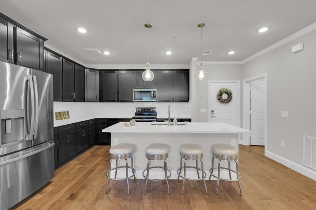 Kitchen with stainless steel appliances, a sink, dark cabinetry, a breakfast bar area, and tasteful backsplash | Image 5