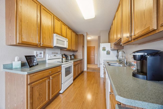 Well maintained galley kitchen with oak cabinets, plenty of storage with pull out shelves in lower cabinets & pantry. Enjoy the newer Bosch dishwasher and built-in-desk. | Image 11
