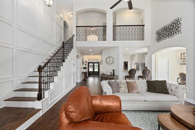 The open floorplan features soaring ceilings, custom built-ins, and a stunning custom millwork wall along the staircase. | Image 9