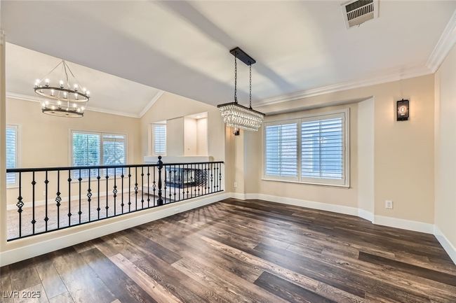 Empty room with a chandelier, dark wood-style flooring, ornamental molding, and lofted ceiling | Image 11