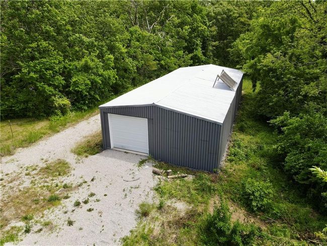 Detached garage featuring a view of trees and gravel driveway | Image 15