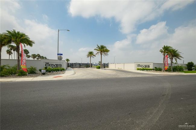 View of asphalt street with street lights, sidewalks, a gated entry, and curbs | Image 21