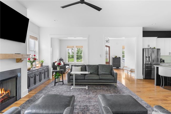 Living area featuring a lit fireplace, light wood-type flooring, ceiling fan, and recessed lighting | Image 8