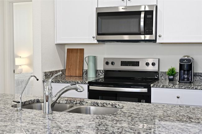 Kitchen featuring white cabinetry, light stone countertops, stainless steel appliances, and a sink | Image 21