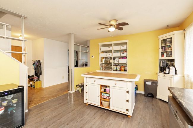Kitchen with beverage cooler, a ceiling fan, light wood-style floors, white cabinetry, and a kitchen island | Image 14