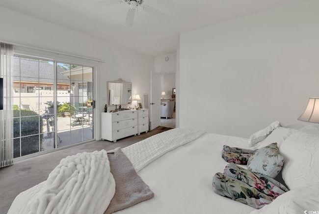 Primary bedroom with direct access to secluded back yard, a ceiling fan, and attached main bathroom | Image 22