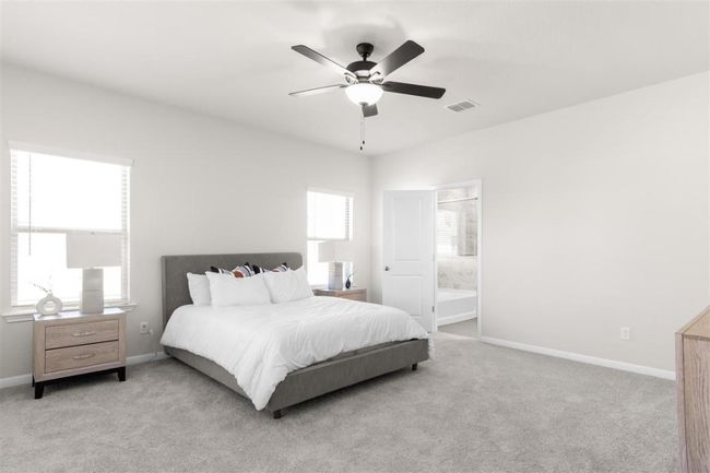 Carpeted bedroom featuring ensuite bath, baseboards, ceiling fan, and visible vents | Image 20